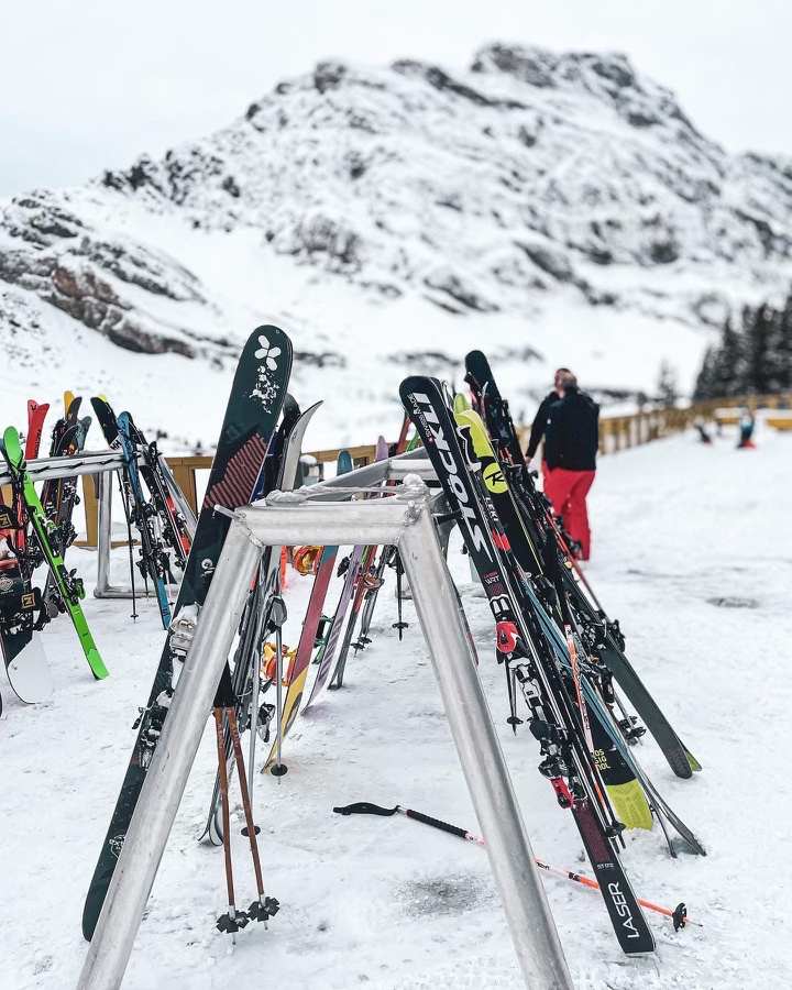 Skis standing on ski rack in front of snowy mountain