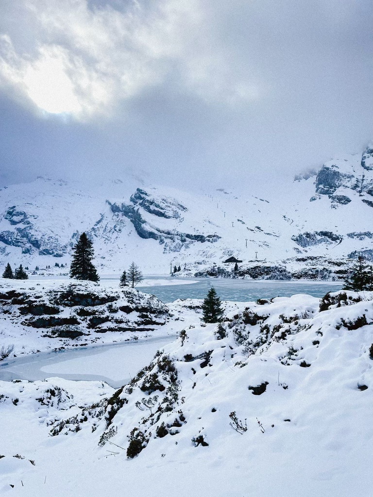 Frozen mountain lake with snowy hills and trees surrounding
