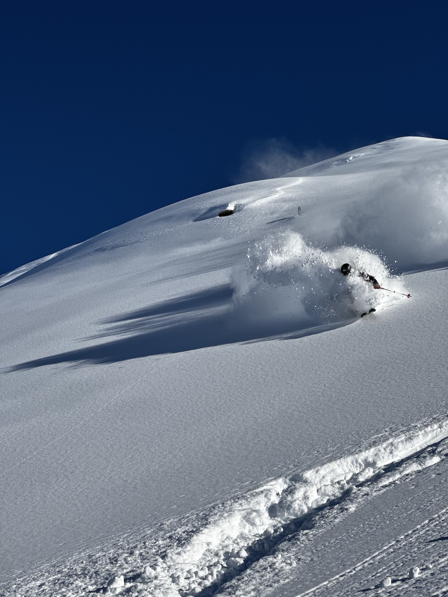 Skier in the powder on a sunny mountainside.