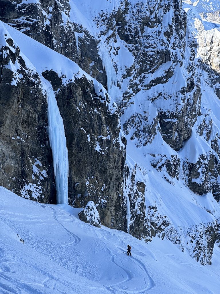 Skier standing next to large ice waterfall