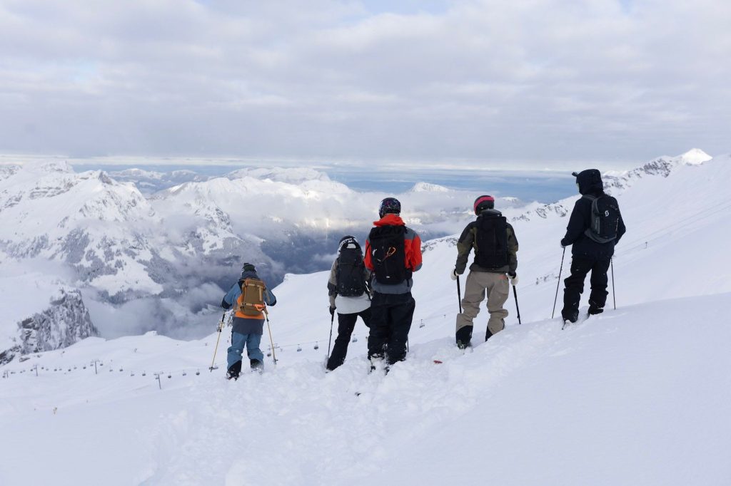 A group of skiers looking at a ski line below