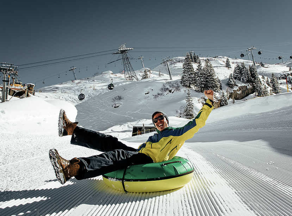 Man on tube sledding down groomed hill