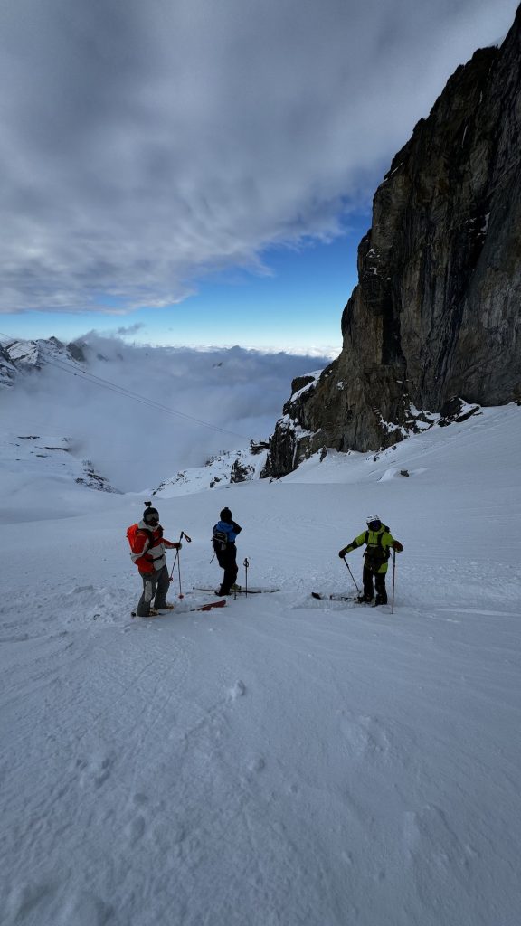 Three skiers standing together smiling for the camera.