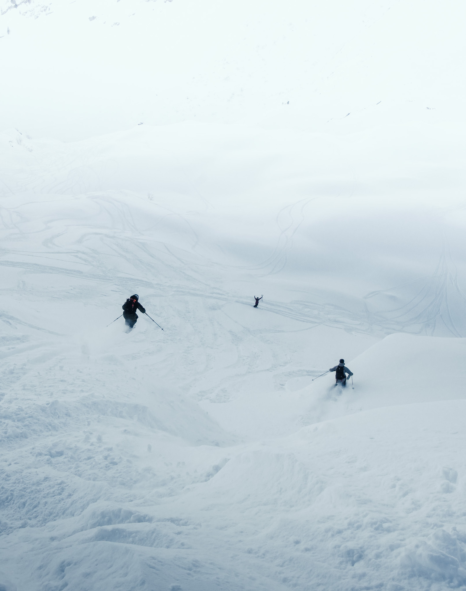Three skiers turning in foggy powder snow