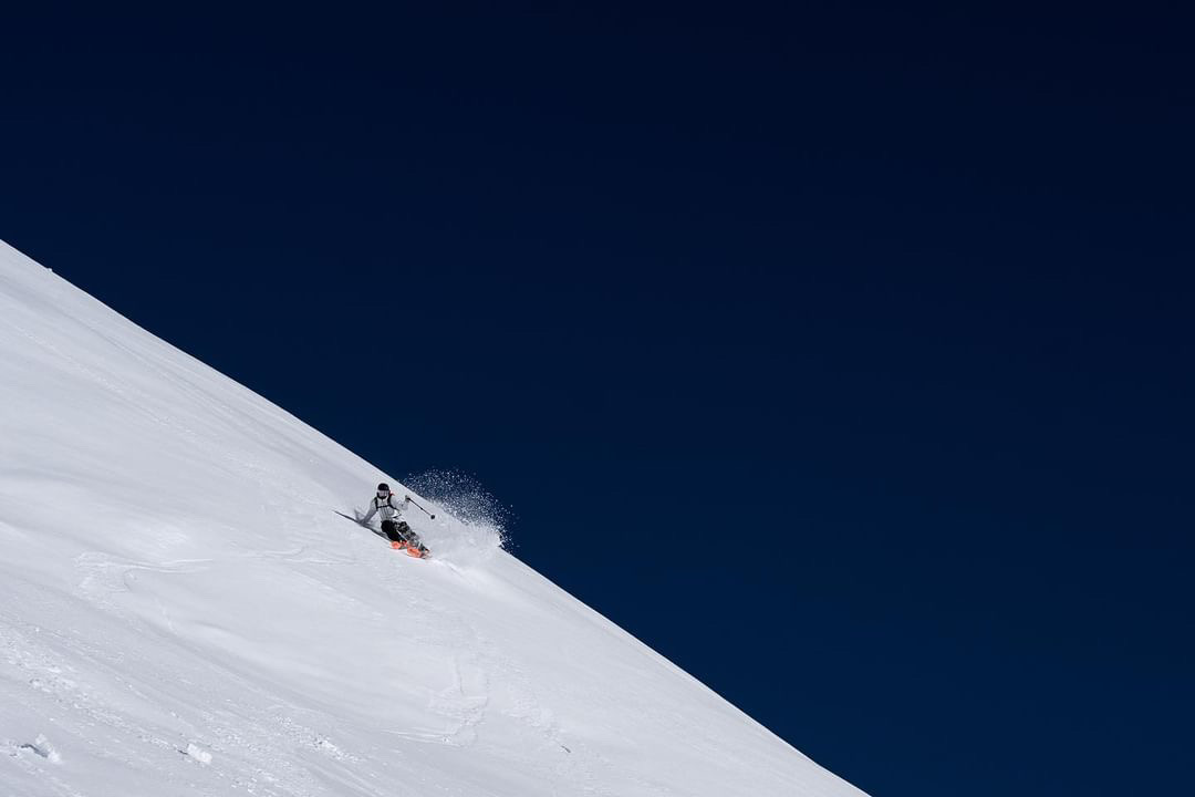 Skier making a turn on chalky snow with a dark blue background