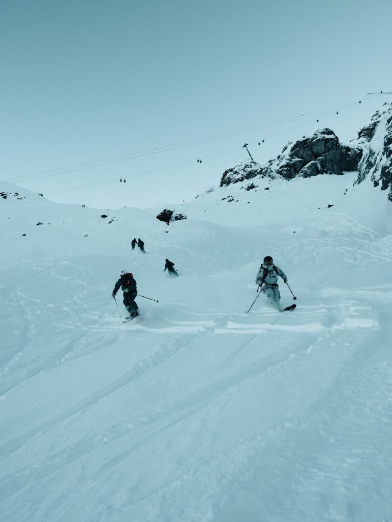 Group of five skiers making turns under a large gondola. 