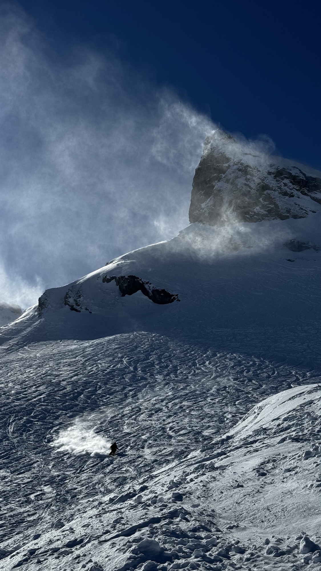 Skier making a turn down a steep snow face.