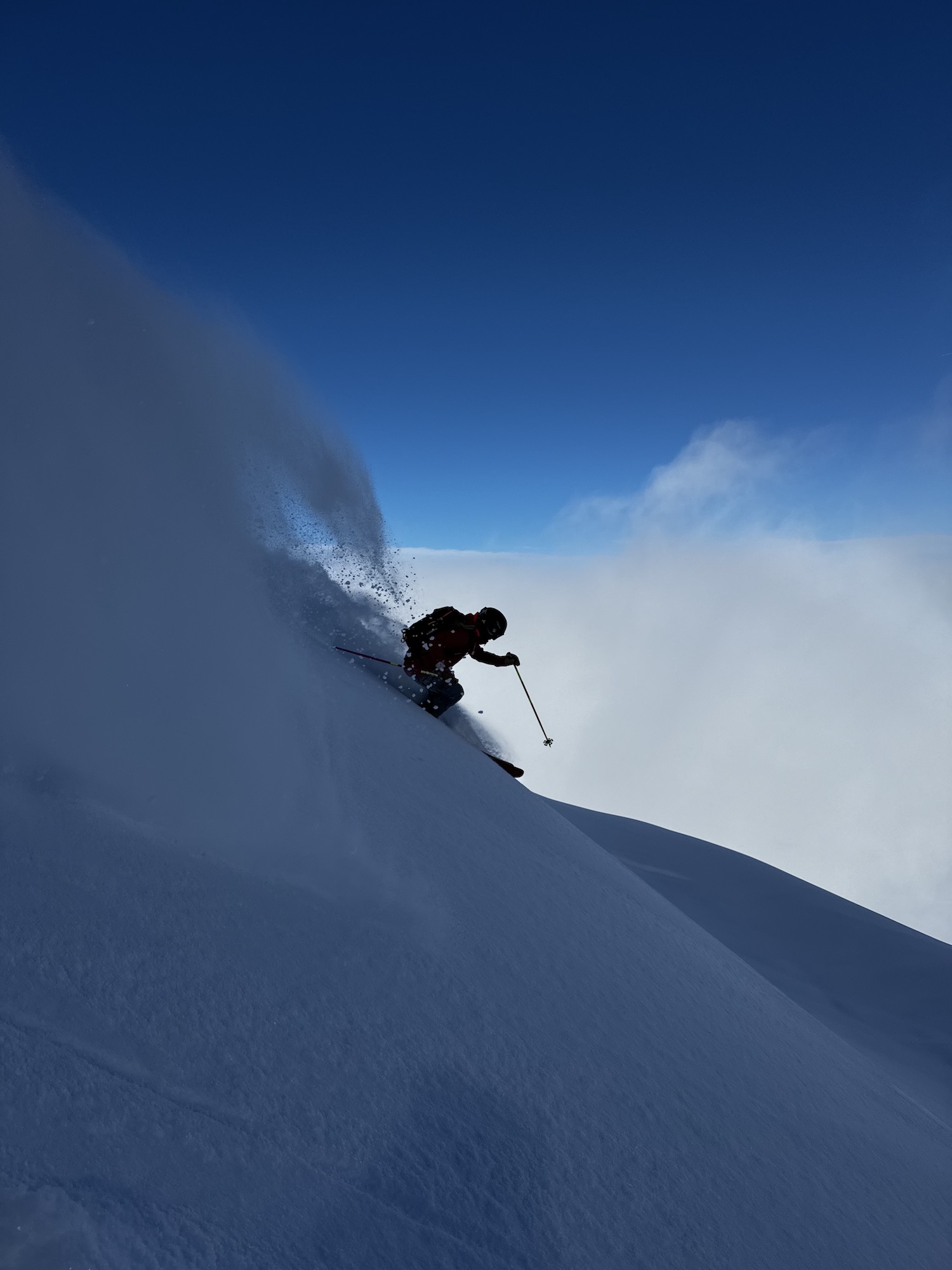 Skier skiing powder snow with a blue sky background.