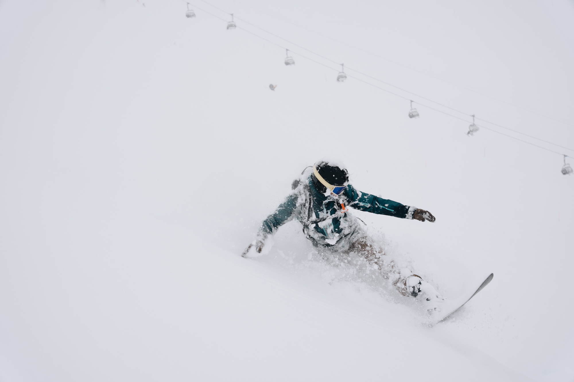 Snowboarder riding through deep powder on a foggy day.
